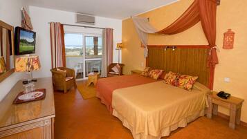 Une chambre d’hôtel avec un grand lit, un bureau avec une lampe, une chaise, une petite table et une vue sur l’extérieur.