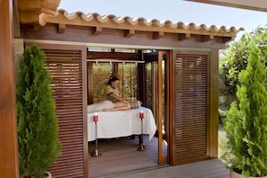 Een spa-ruimte met een bed, houten latten en een kaars.
