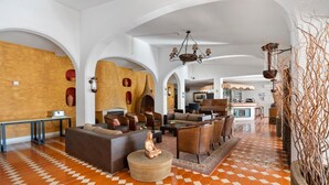 A spacious lobby with a checkered floor, a central seating area with sofas and chairs, a coffee machine, and a decorative Buddha statue. - Hotel Cerro da Marina (Albufeira)