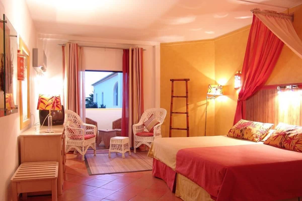 Ein Hotelzimmer mit Bett, zwei Stühlen, einem Schreibtisch, einer Leiter und Blick ins Freie.