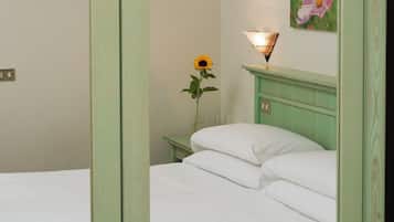 Una habitació amb un llit, una tauleta de nit, una làmpada i un quadre a la paret.