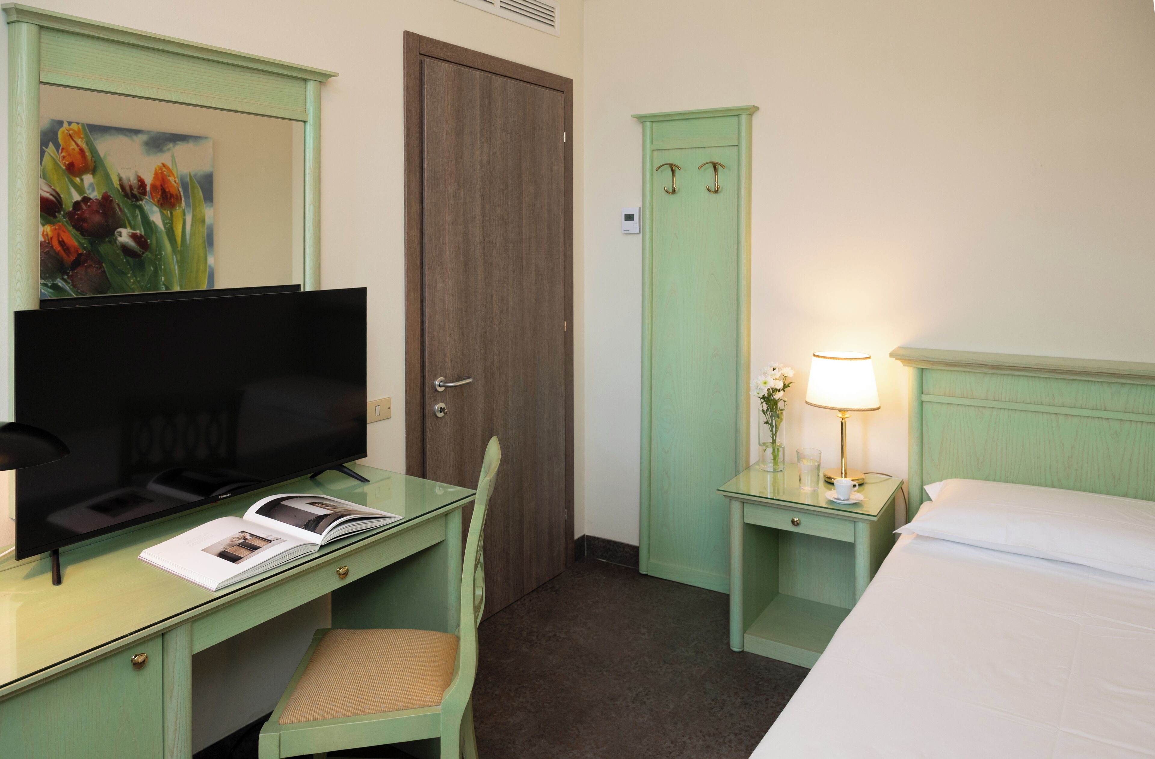 A hotel room with a desk, chair, television, and a bed.