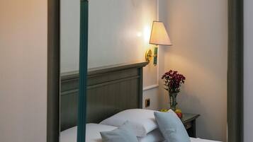 Una habitación de hotel con cama, mesita de noche, lámpara y espejo.