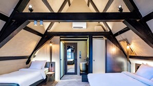 Un dormitorio con dos camas, piso de madera y techo abovedado con vigas a la vista.