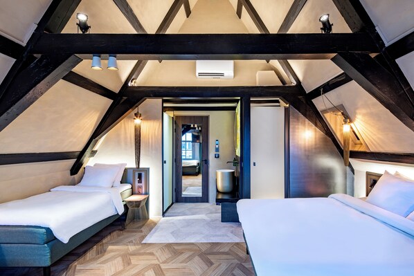 A bedroom with two beds, a wooden floor, and a vaulted ceiling with exposed beams. - Mister Highland Hotel (Amsterdam)