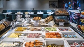 Un bufé con diversos alimentos y un área de estar con bancos acolchados azules.