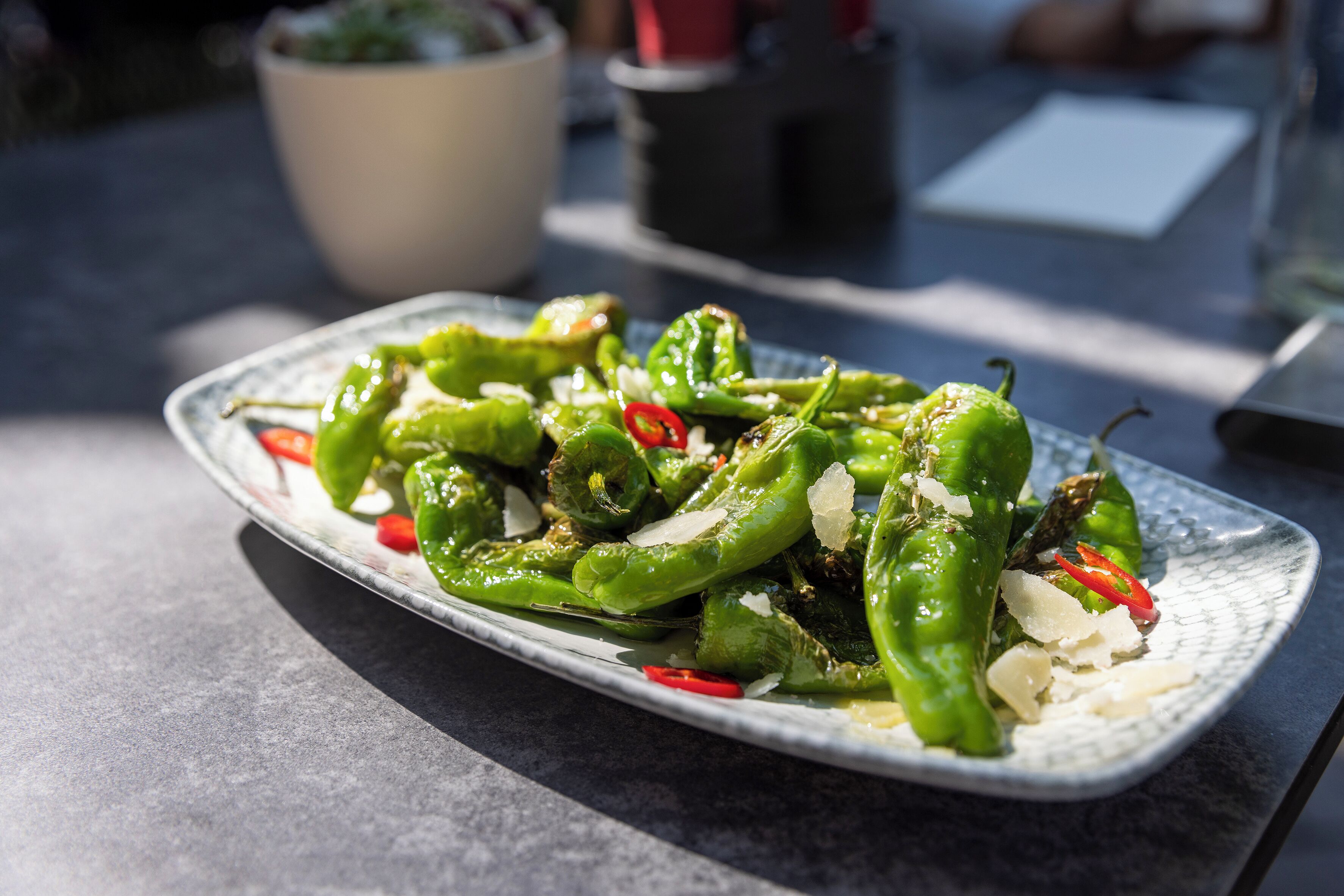 Een bord met groene paprika, rode chilischijfjes en kaas op een tafel.