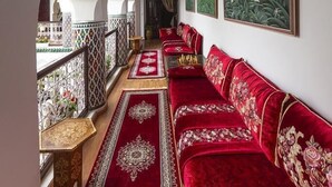 A corridor with a red carpet, a sofa, and a wall with framed artwork. - Riad Maison Belbaraka (Marrakech)