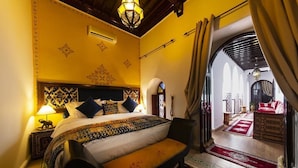 A room with a bed, a bench, a lamp, and a view through an archway. - Riad Maison Belbaraka (Marrakech)