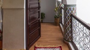 A corridor with a wooden door, a red carpet, and a tiled railing. - Riad Maison Belbaraka (Marrakech)