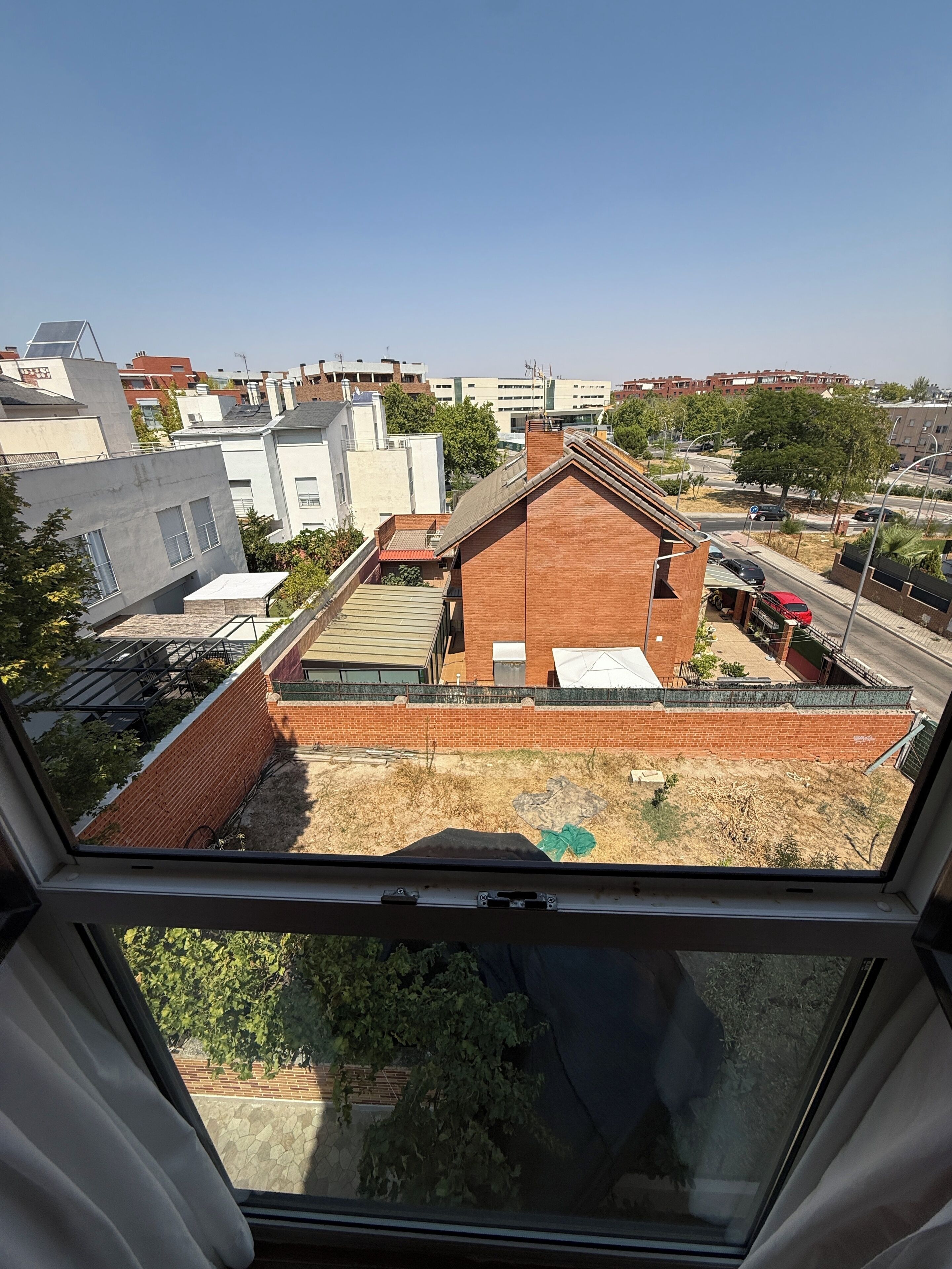 Ein Wohngebiet mit einer Mischung aus modernen und traditionellen Geb äuden, einem klaren Himmel und Blick durch ein Fenster.