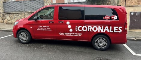 A red van with 'Hostal Coronales' branding parked on a street.