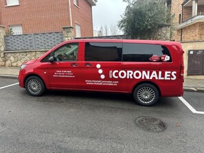 Una camioneta roja con el rótulo 'Hostal Coronales' estacionada en una calle.