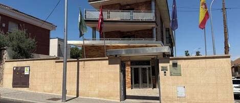 A two-story building with a balcony, a door, and multiple flags.