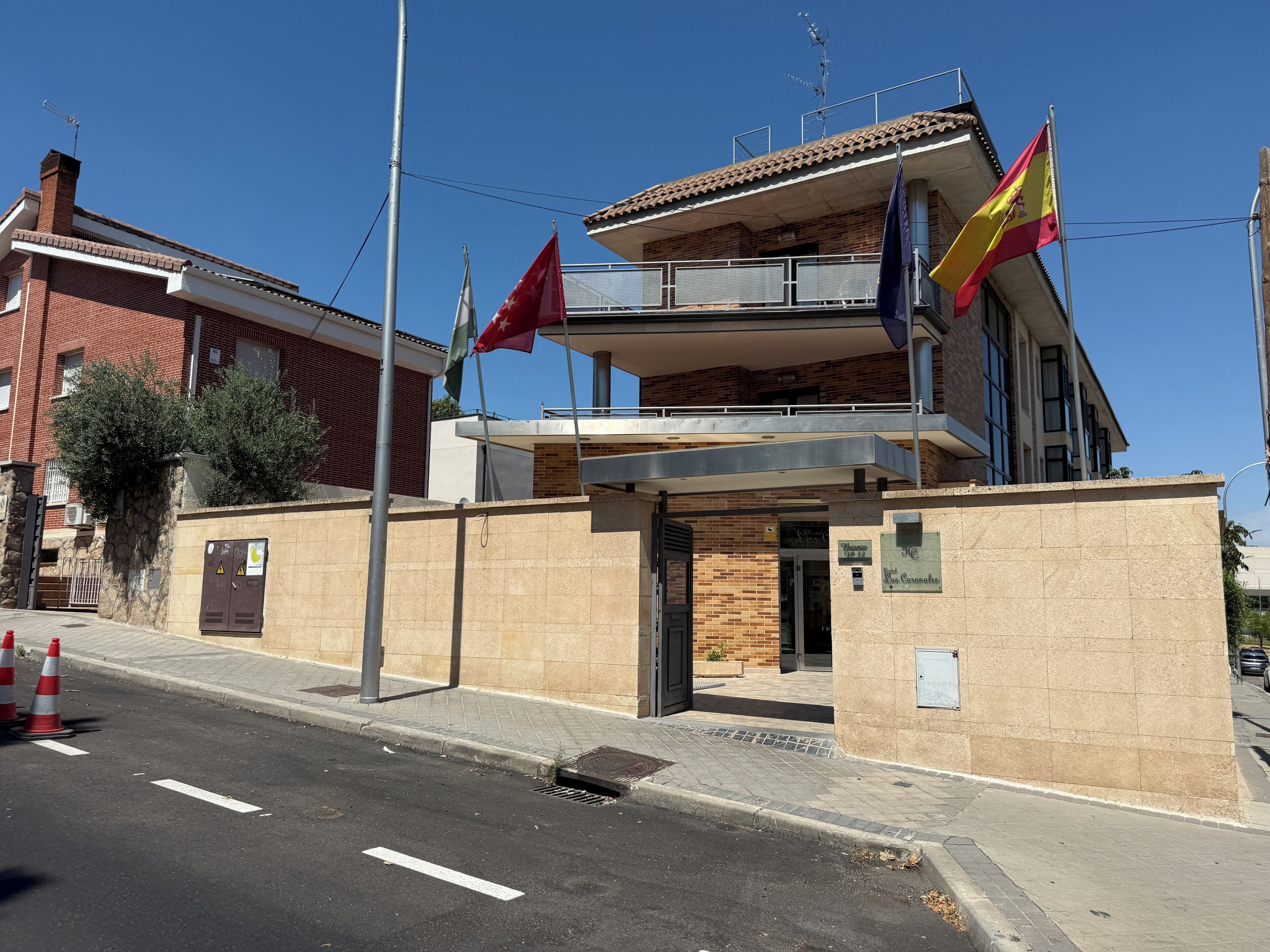 Un edificio de varios pisos con un balcón, una bandera y un letrero que indica un hotel.