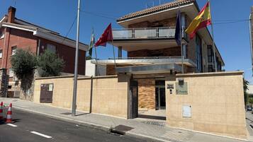 Un edificio de varios pisos con un balcón, una bandera y un letrero que indica un hotel.
