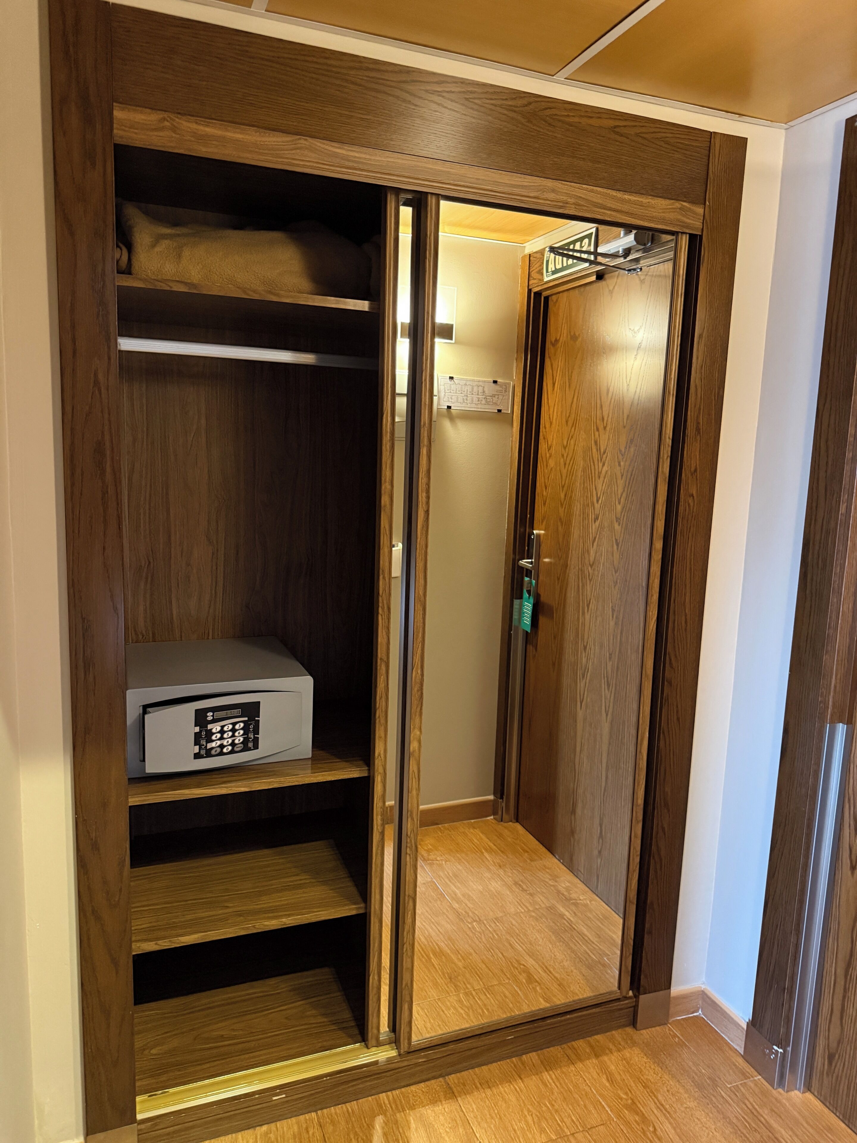 A wooden closet with a built-in safe and a door leading to a stairwell.