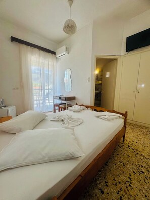 A hotel room with a bed, a desk, a chair, a wardrobe, and a television. - Asteria (Zakynthos)