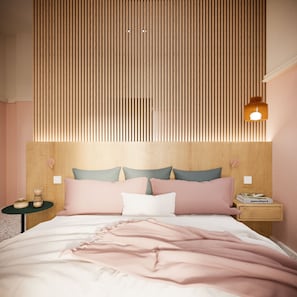 Quarto com cabeceira de ripas de madeira, cama com roupa de cama rosa, duas mesas de cabeceira com abajures e uma mesinha de cabeceira com um livro.