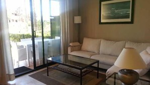 A living room with a glass coffee table, a sofa, a lamp, and a painting on the wall. - El Delfin Verde (Torroella de Montgri)