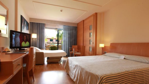 A hotel room with a bed, a desk with a computer, a chair, and a television. - El Delfin Verde (Torroella de Montgri)