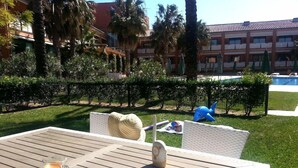 An outdoor seating area with a table, chairs, a cup of coffee, and a pool in the background. - El Delfin Verde (Torroella de Montgri)