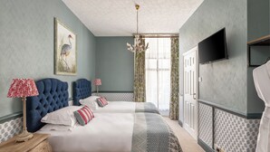 A hotel room with two beds, a TV, a chandelier, and a painting on the wall. - The Royal Hotel (Bath)