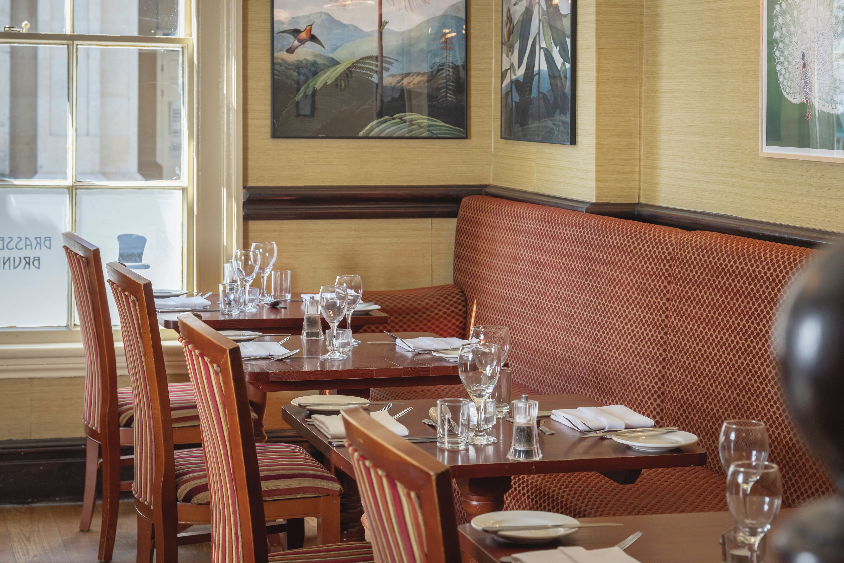 A restaurant with wooden tables and striped cushioned booths.