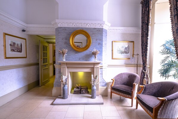 A room with a marble fireplace, two framed pictures, and a large window with curtains. - The Royal Hotel (Bath)