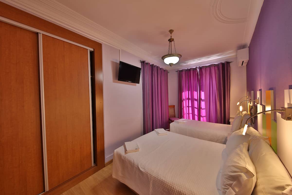 Een hotelkamer met twee bedden, een televisie en een schuifdeur.