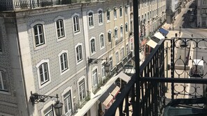 Uitzicht op een stadsstraat met gebouwen, een heldere lucht en een metalen hekwerk.