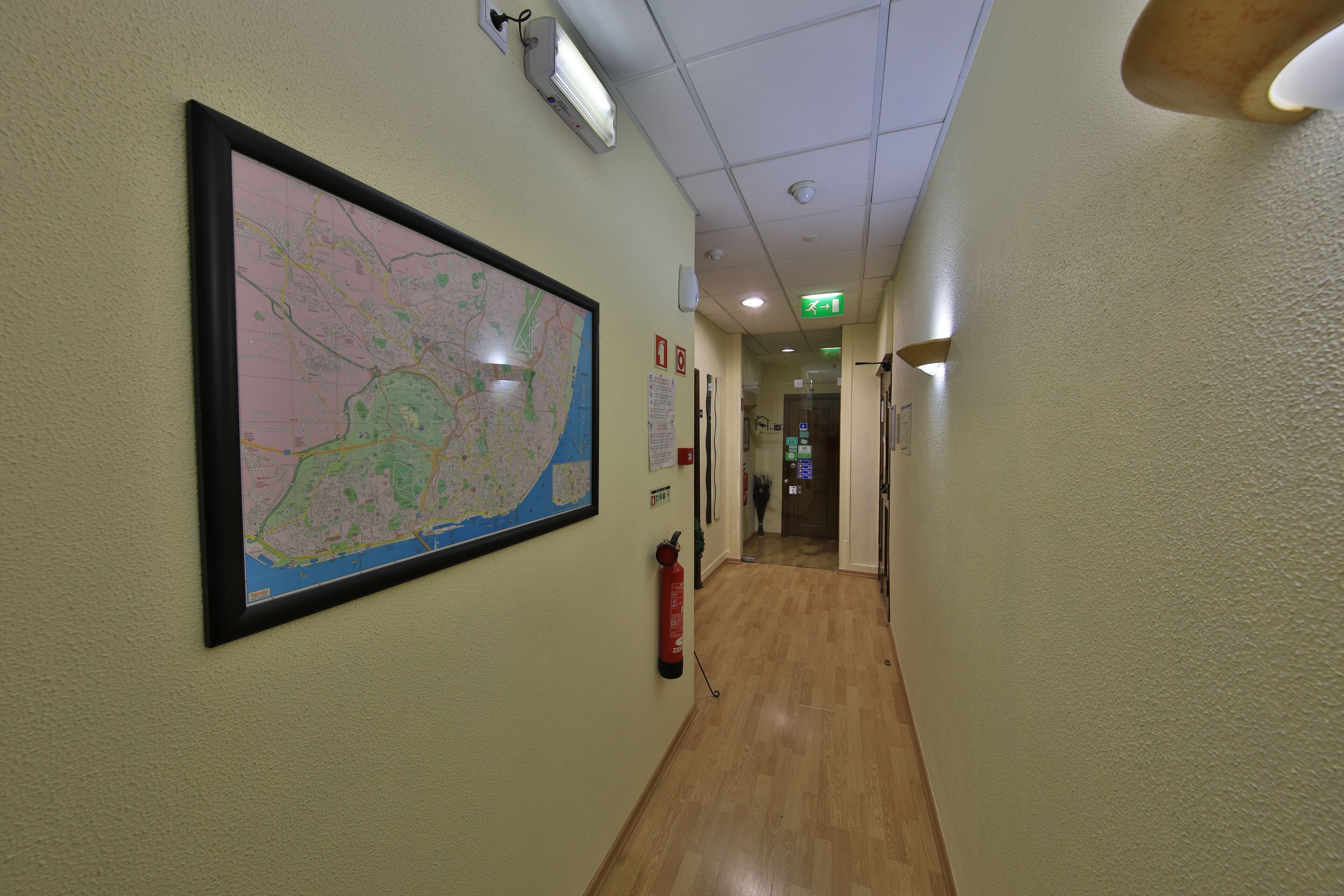 Ein Flur mit einer großen Karte an der Wand, einem Feuerlöscher und einem Hinweisschild für den Notausgang.