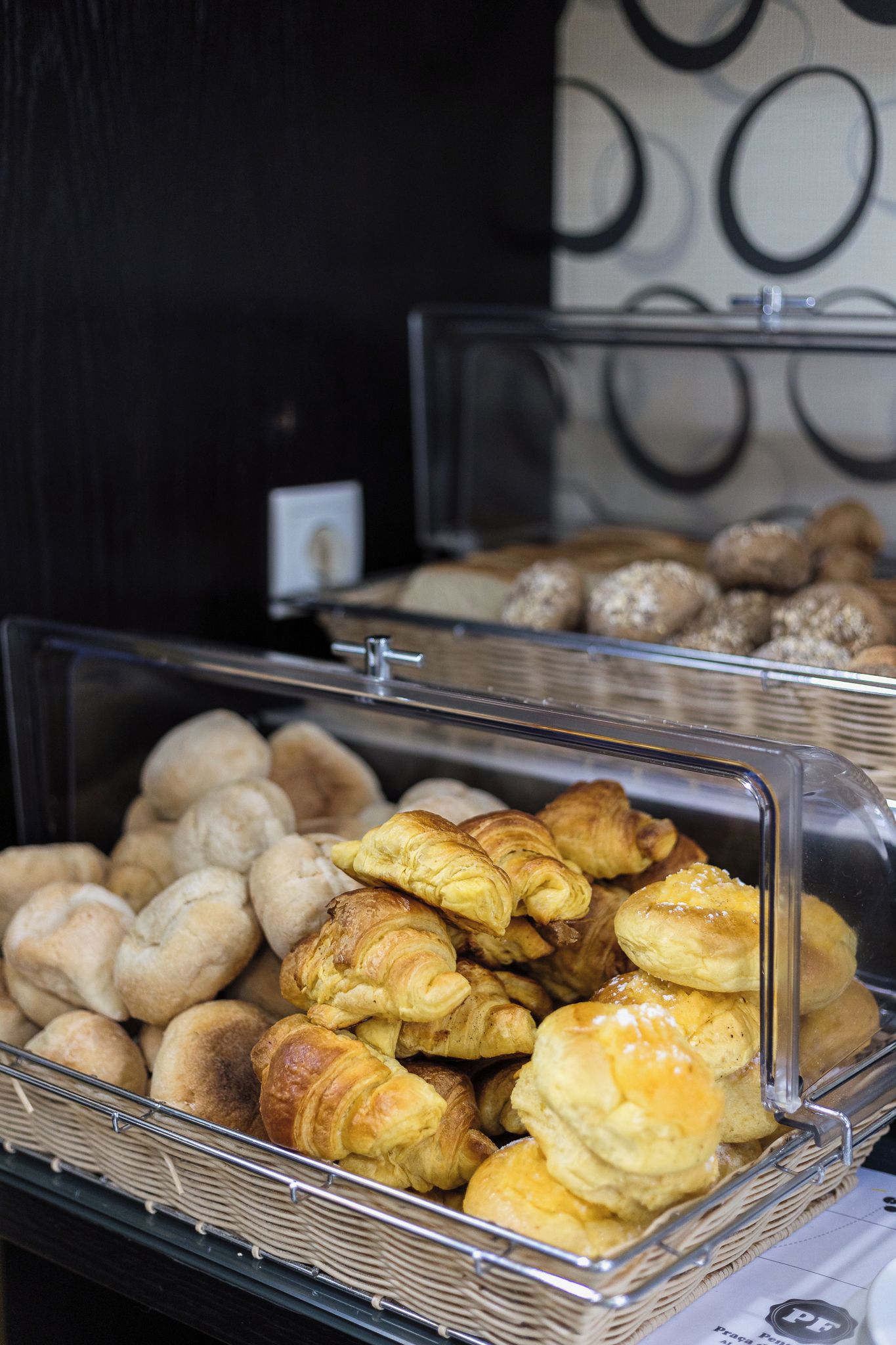 A display case with various baked goods, including croissants and bread rolls.