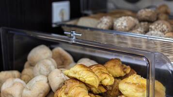 Una vitrina con diversas opciones de panadería, incluyendo cruasanes y bollos.