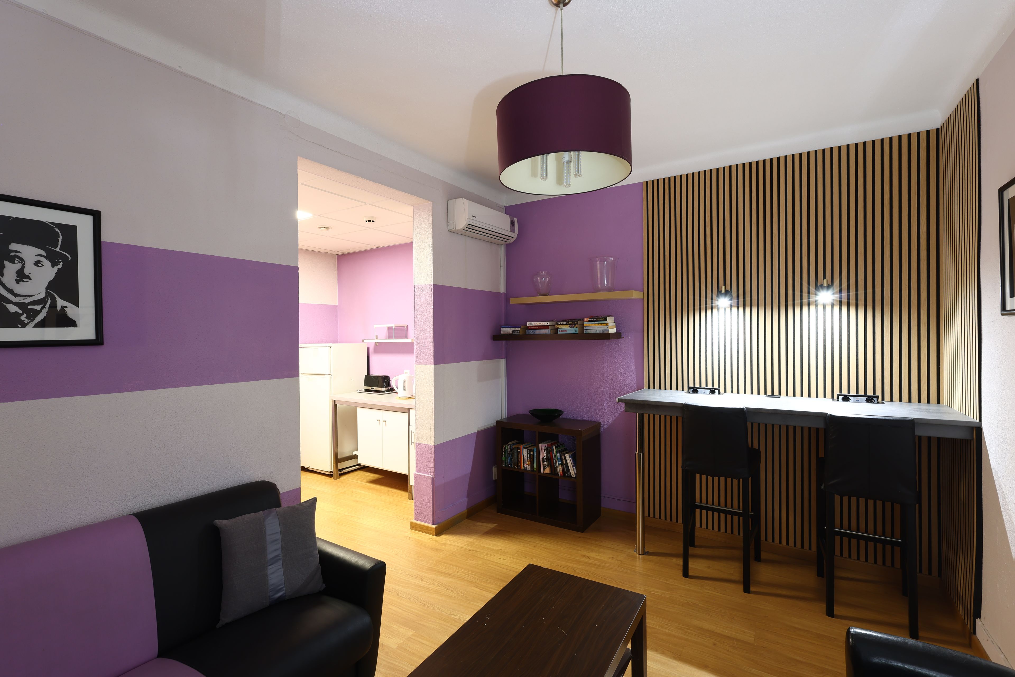 A modern living room with a sofa, a coffee table, and a dining area with a bar. There is a kitchen in the background.