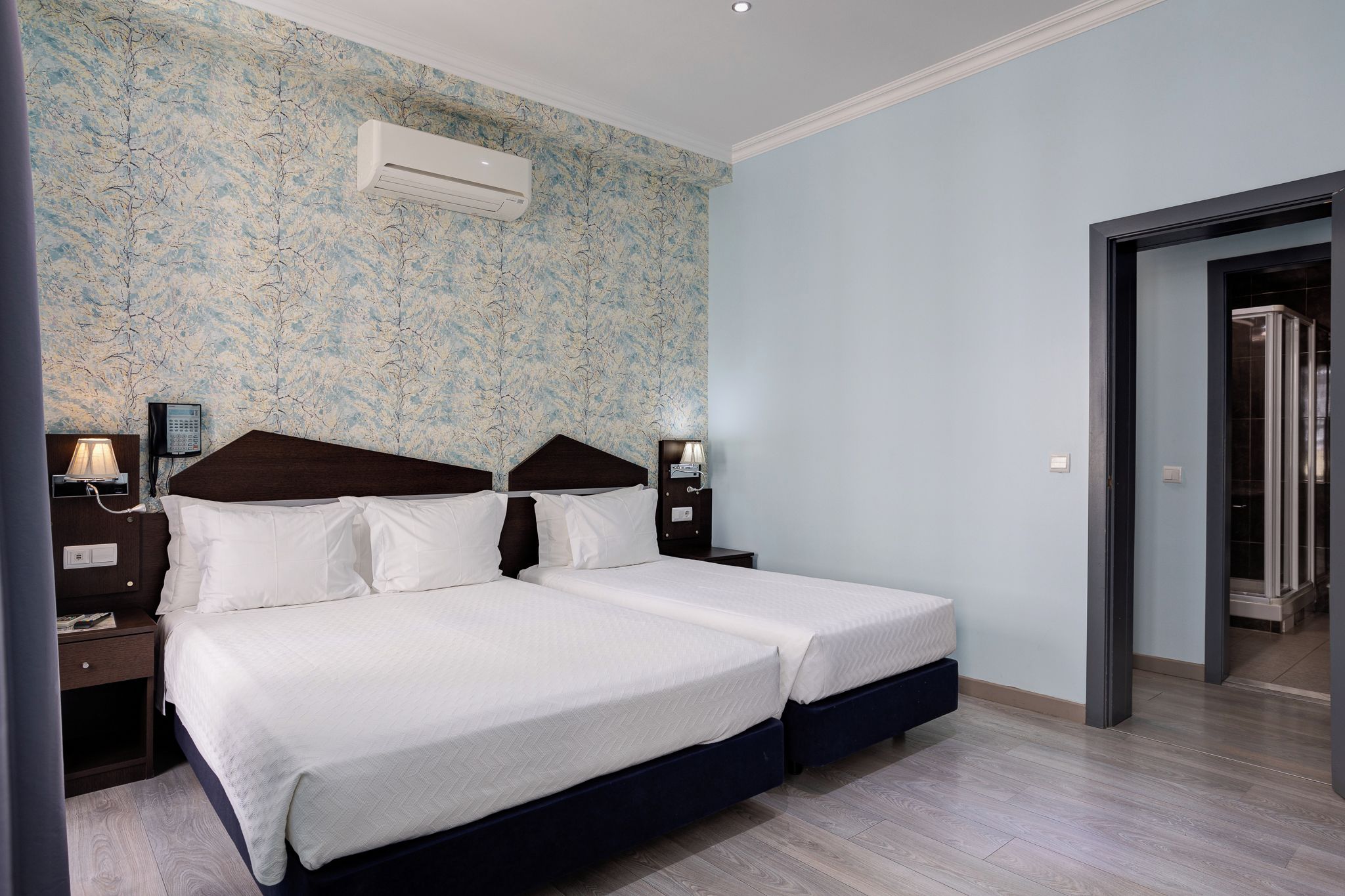 Ein Hotelzimmer mit einem Doppelbett, Nachttischen, einem Telefon und einer Klimaanlage.