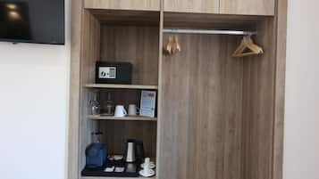 A wooden wardrobe with a flat-screen TV mounted above it, a small shelf with a coffee maker, and a black mini-fridge.