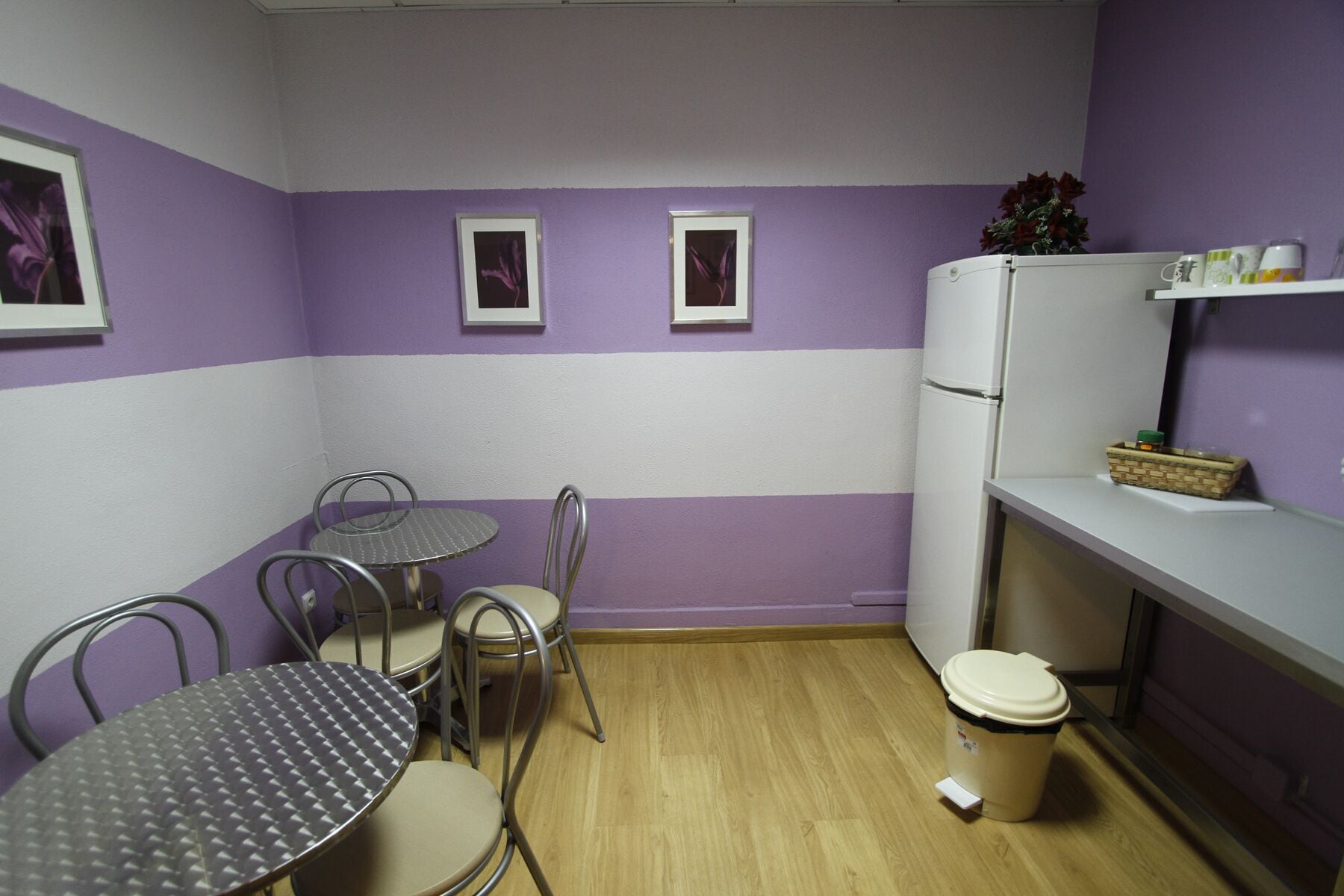 A compact kitchen with a dining area, featuring a refrigerator, a sink, and a small table with chairs.