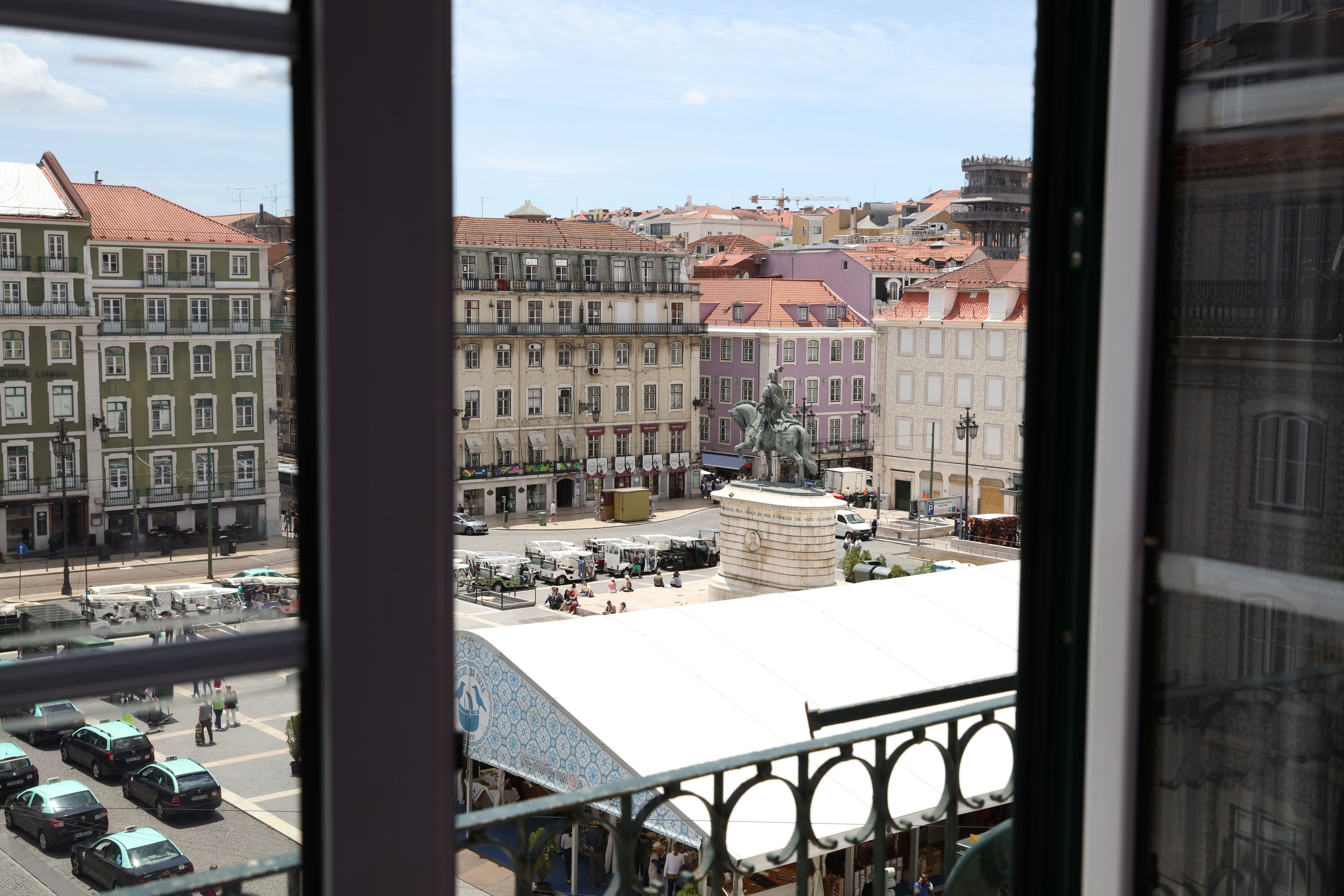 Vista de un paisaje urbano con edificios, una estatua y vehículos estacionados.