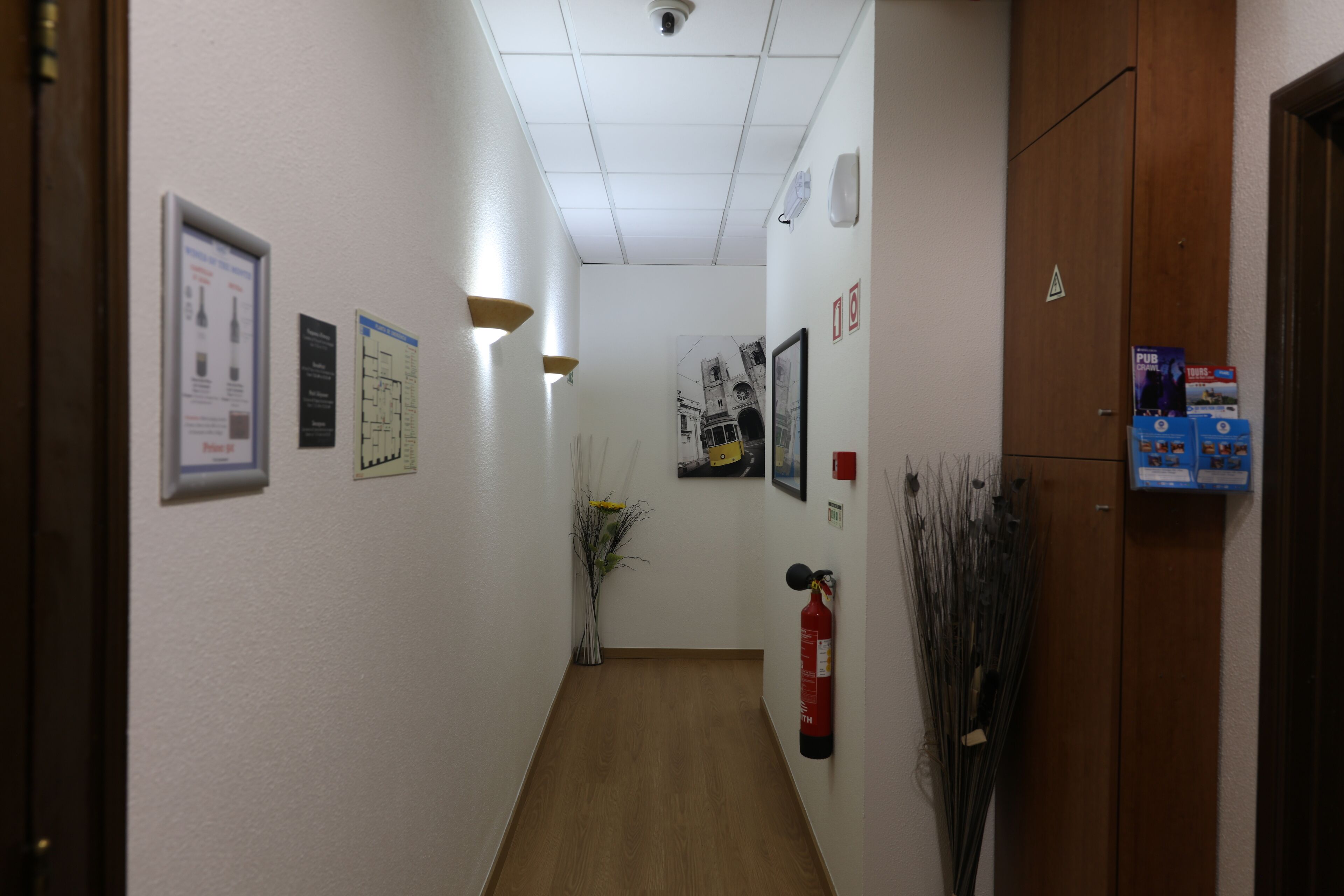 A hallway with a wooden floor, white walls, and various signs and decorations.