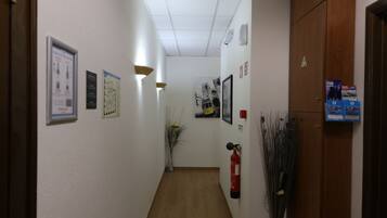 A hallway with a wooden floor, white walls, and various signs and decorations.