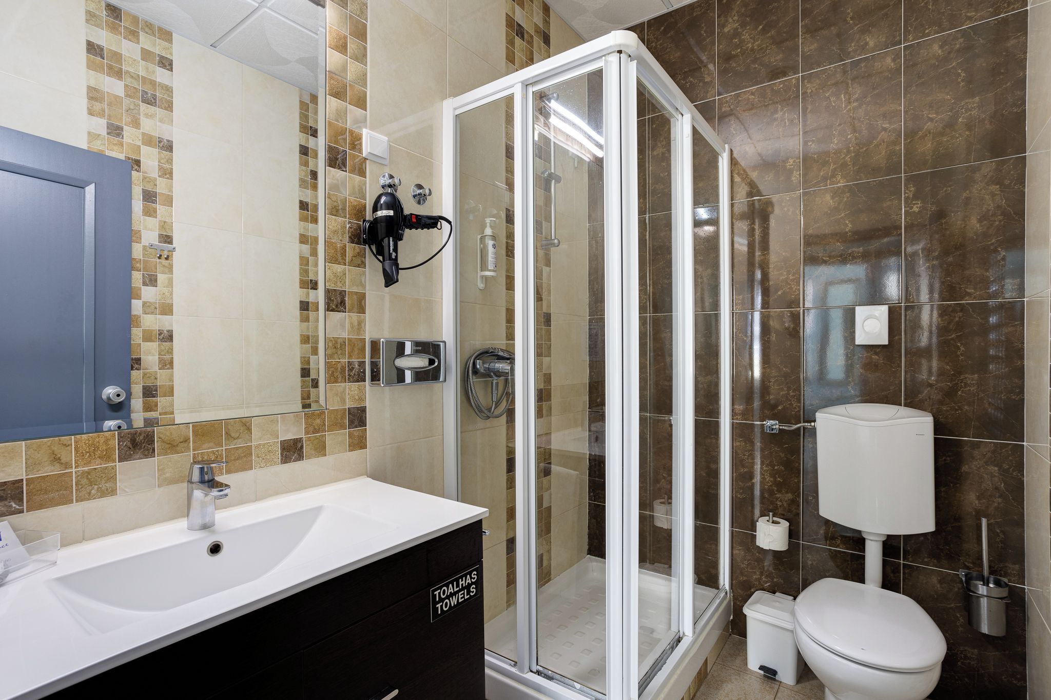 Une salle de bain moderne avec une douche à parois de verre, un lavabo blanc et des toilettes.