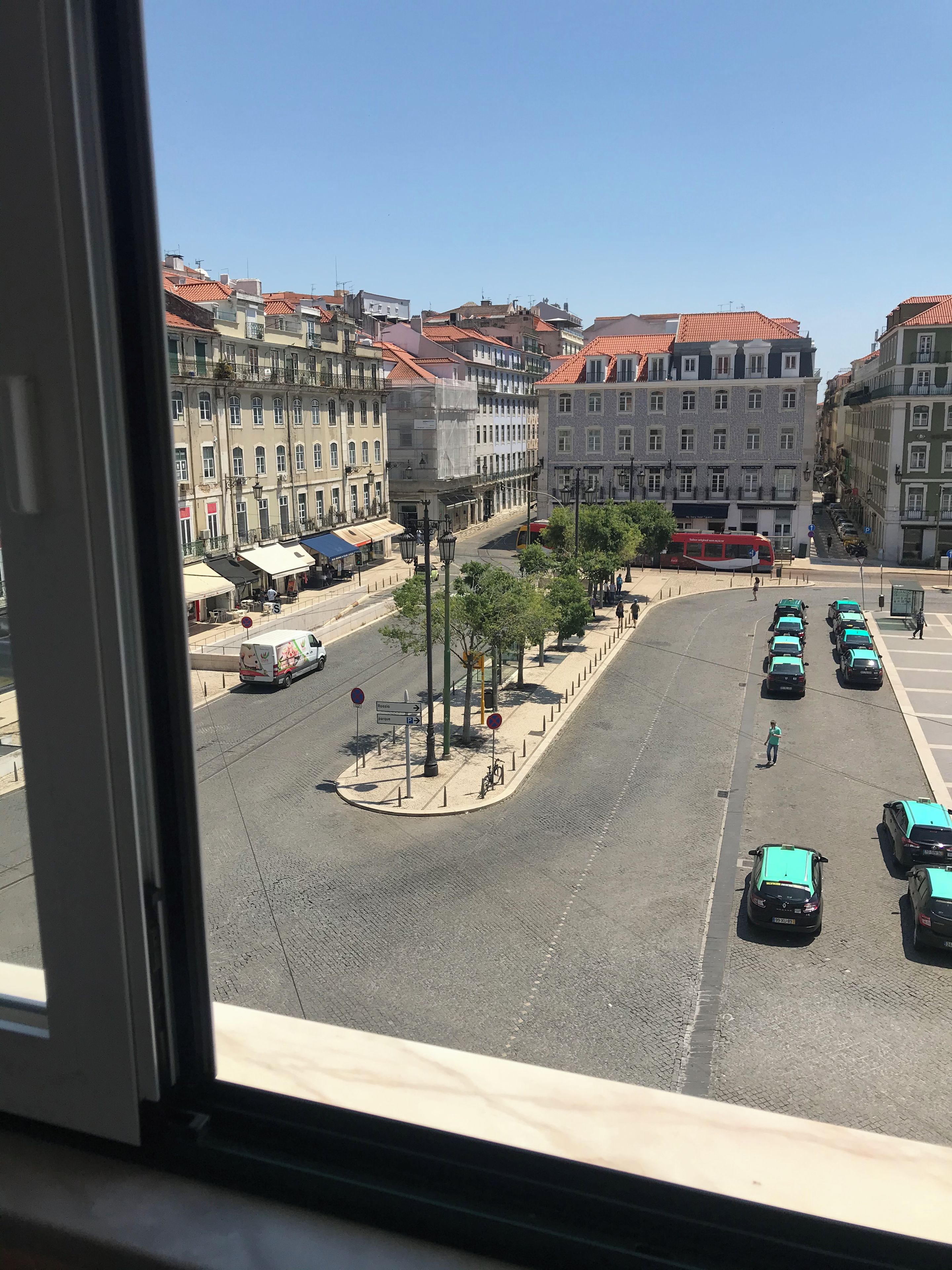 Une vue de rue avec des immeubles, un autobus et des voitures garées.