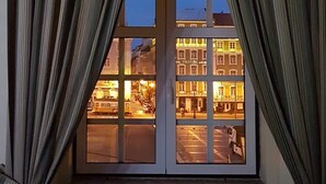 Een raam met gordijnen, een tafel en twee stoelen in een kamer.