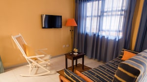 A hotel room with a bed, a rocking chair, a small table with a lamp, and a TV on the wall. - Apartamentos Mayoysa (Brena Baja)