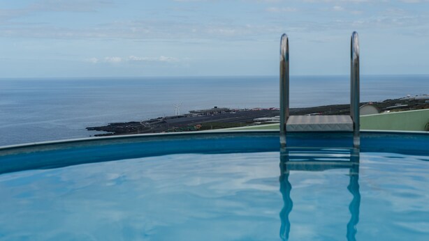 A swimming pool with a view of the ocean and a distant shoreline. - Apartamentos Mayoysa (Brena Baja)