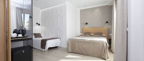 Une chambre d’hôtel moderne équipée d’un lit, de tables de chevet, d’un bureau avec une machine à café et d’une armoire.