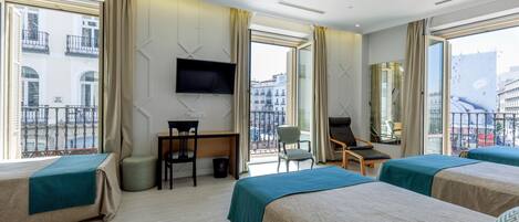 A hotel room with two beds, a desk, a chair, a TV, and large windows with a city view.