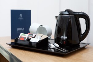 A coffee maker, a tray with coffee pods, and a spoon set on a table.