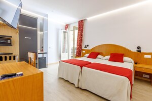 Moderni hotellihuone, jossa on sänky, yöpöydät, työpöytä ja televisio.